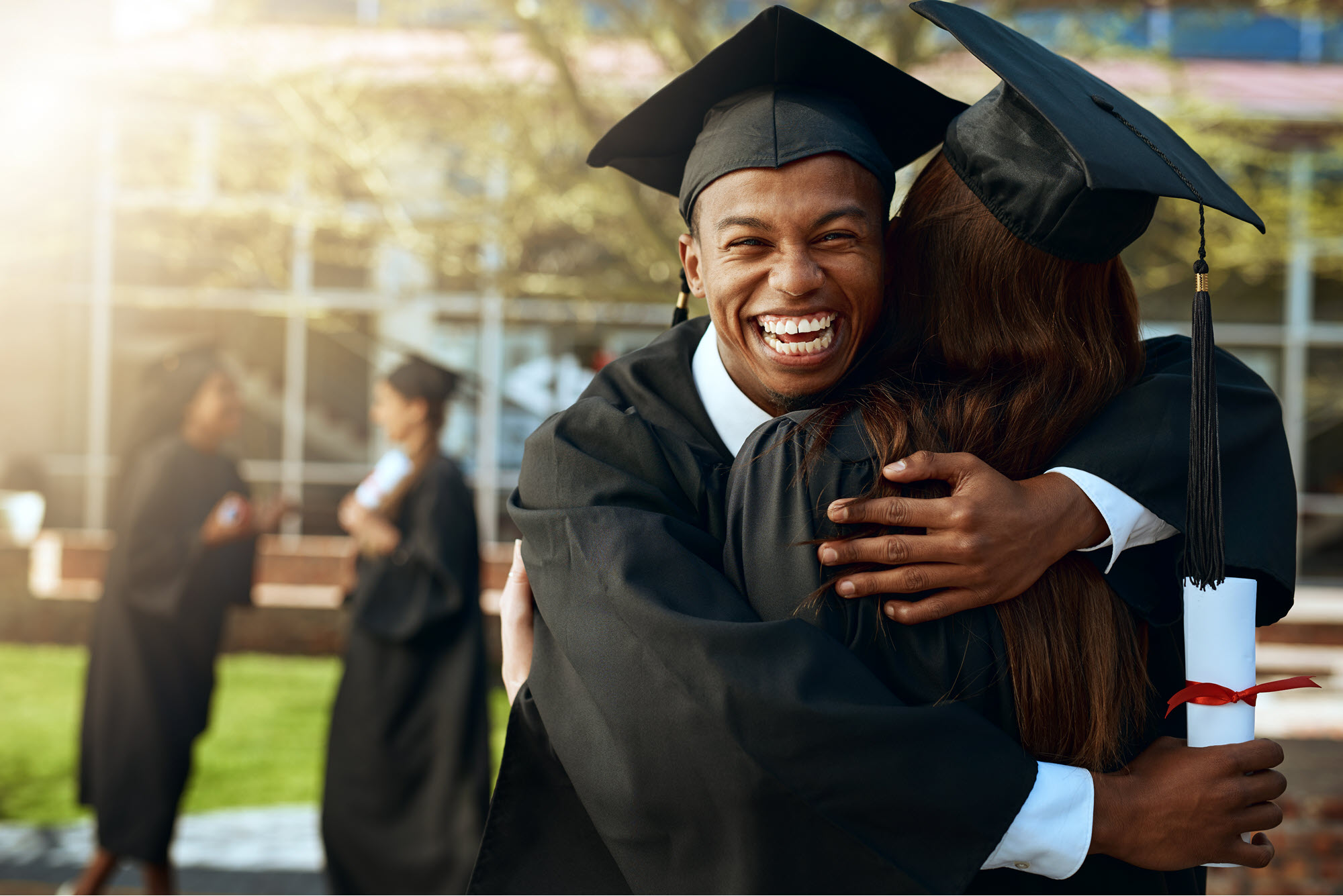 High school male graduate hugging another graduate
